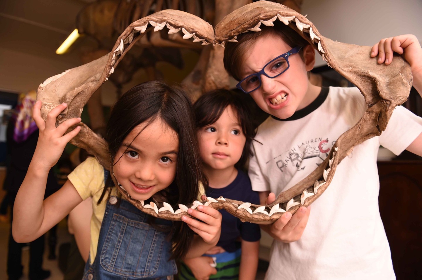 three young children looking through the skeleton of a whale's jaw.
